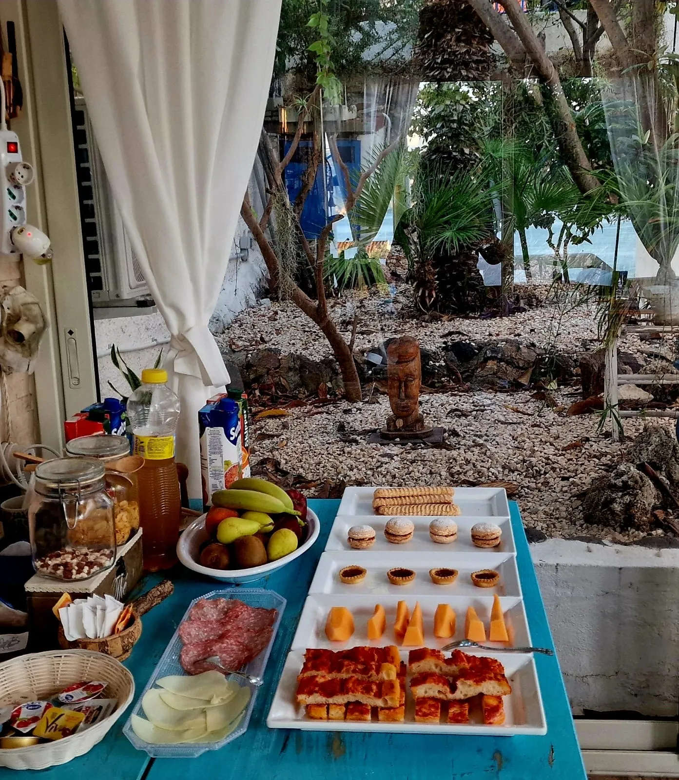 Il buffet della colazione sul tavolo turchese: biscotti, crostatine, frutta e focaccia