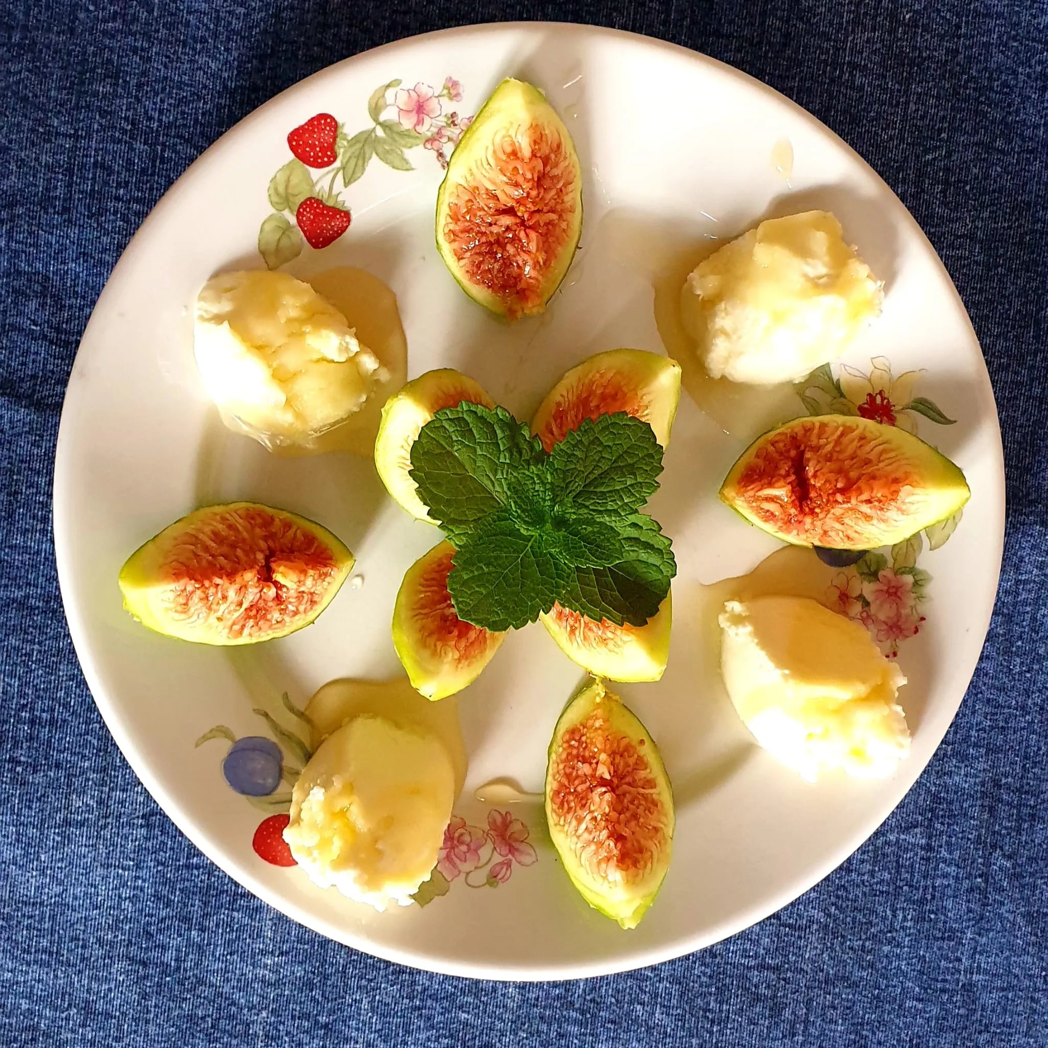 Piatto della colazione con fichi freschi, ricotta e miele guarnito con foglie di menta