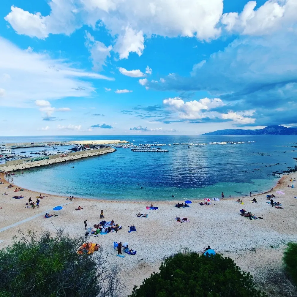 La spiaggia di Cala Gonone: la mezzaluna di ciottoli chiari, la baia turchese e il porticciolo