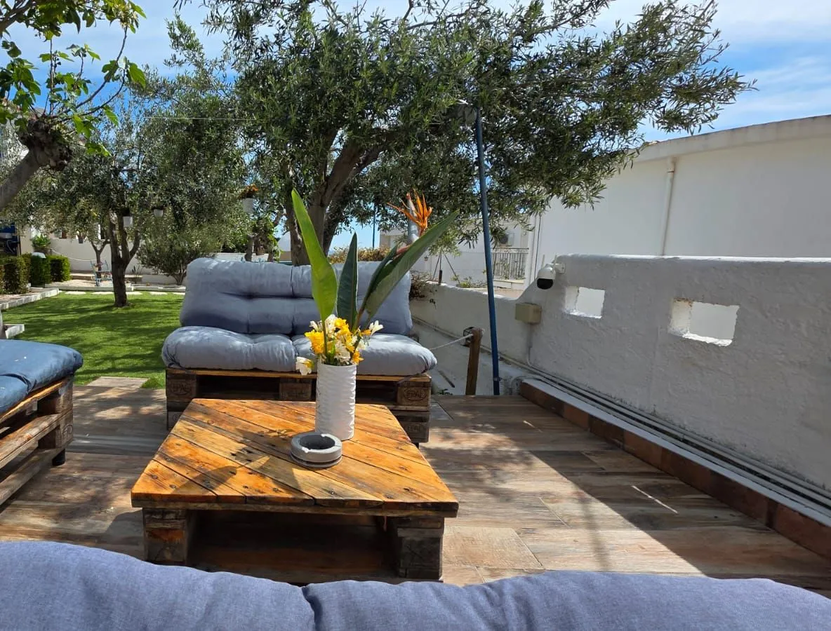 I divani in pallet della terrazza con il tavolino e il vaso di fiori, e il giardino verde sullo sfondo